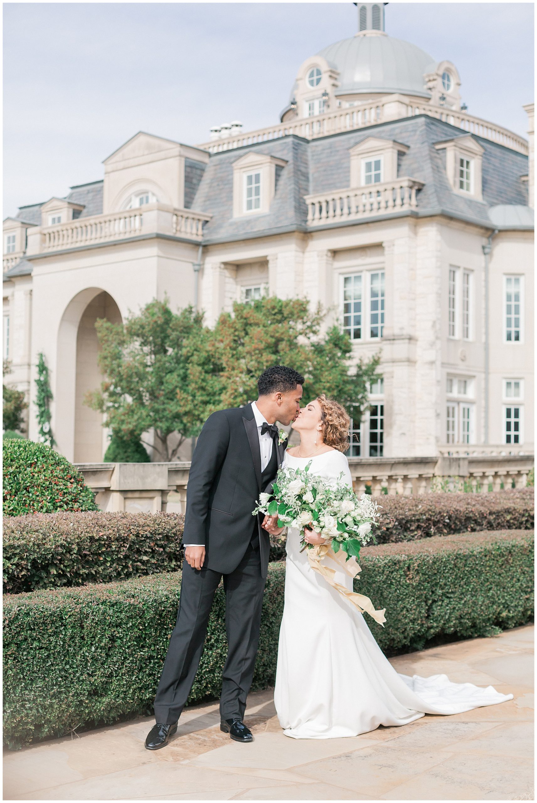 Couple kissing in front of beautiful wedding venue