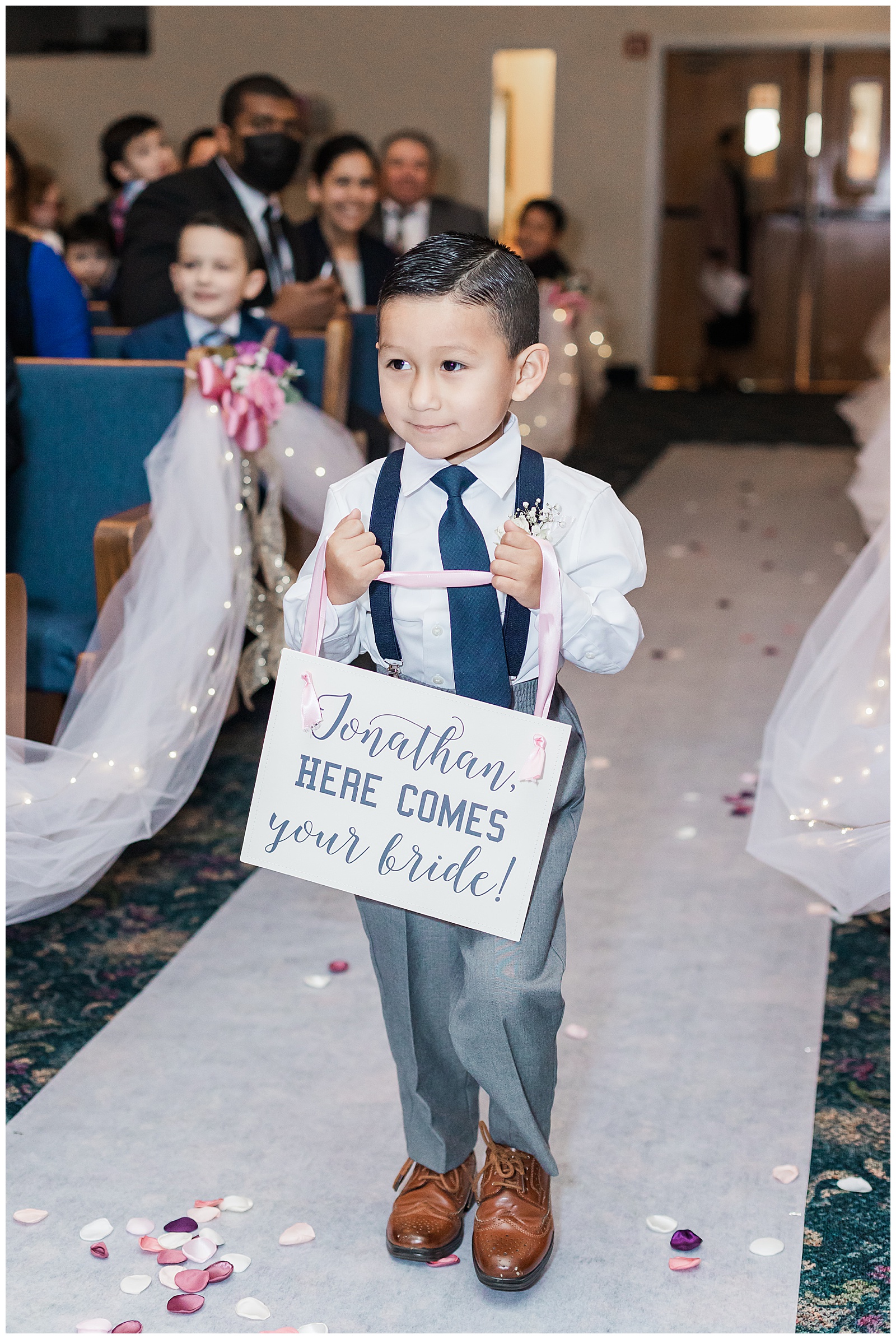 Boy carrying "Here comes your bride!" sign