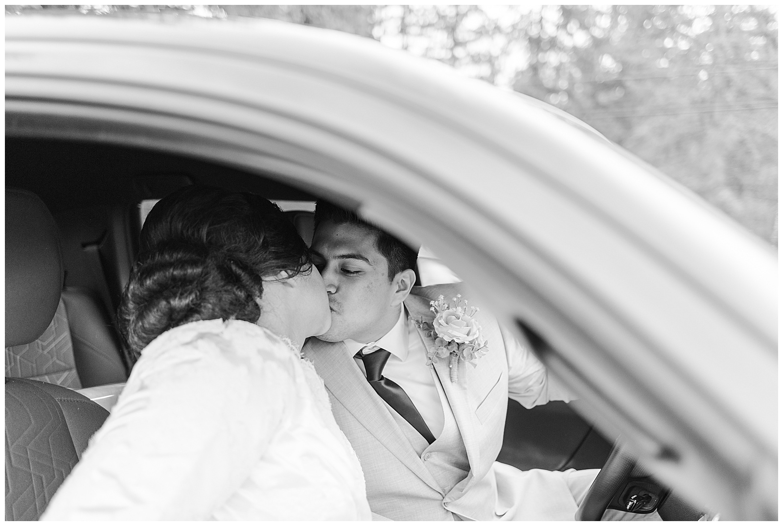 Bride and groom kissing in getaway car