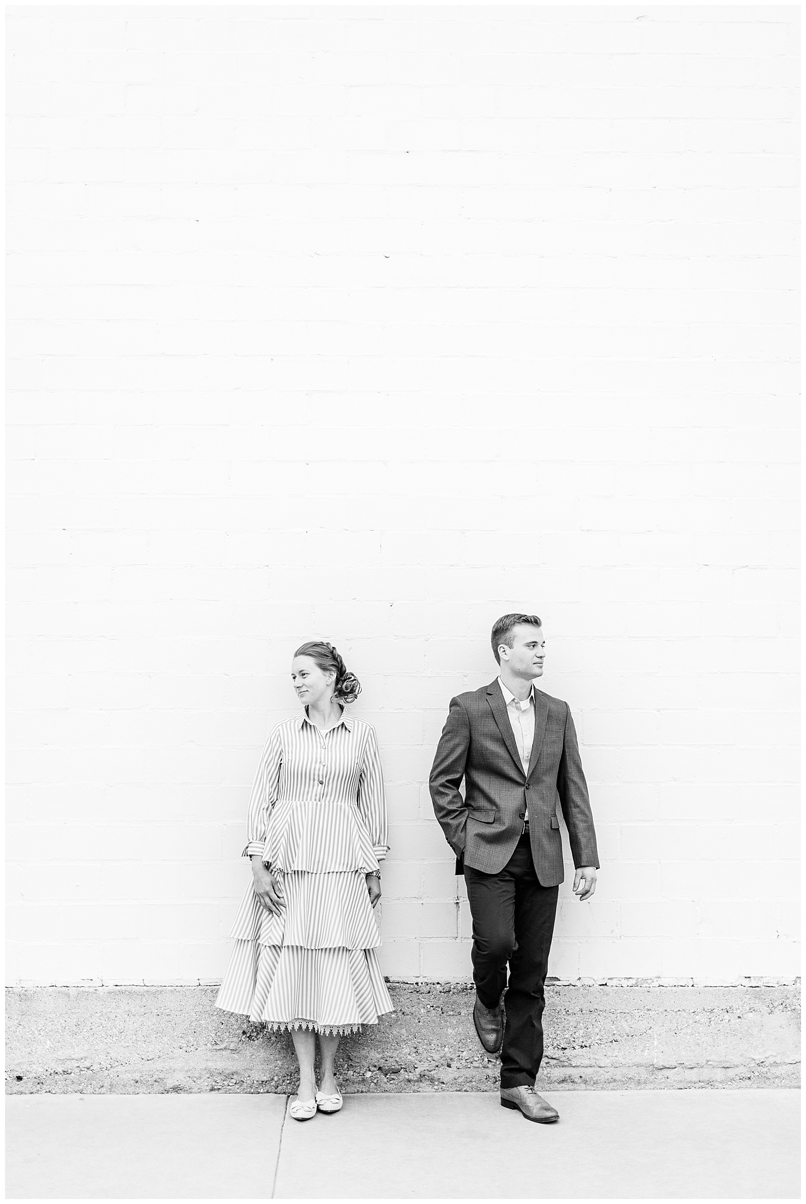 Couple leaning against wall looking in opposite directions.