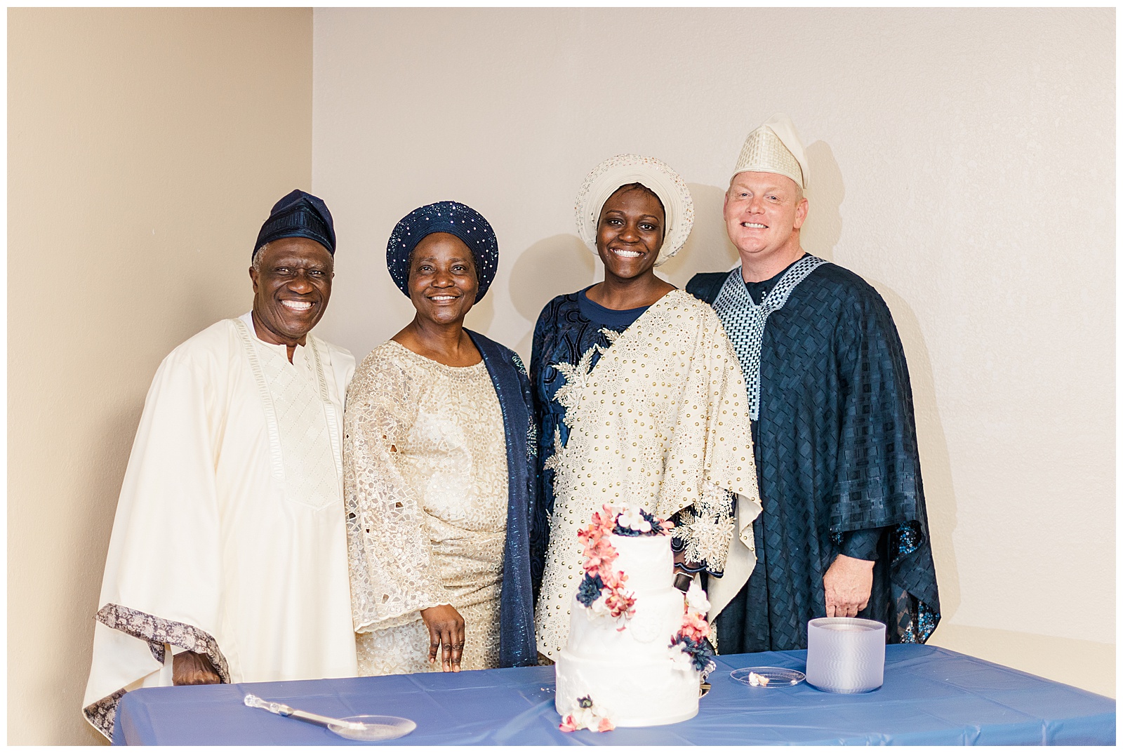 Bride and groom with bride's parents posing in front of cake at Nigerian reception